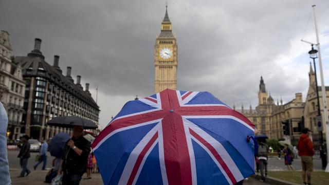 Ein Fußgänger trägt einen Schirm mit dem Union-Jack. Im Hintergrund ist Big Ben zu sehen.