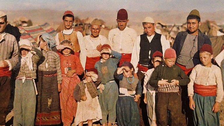 Ein Gruppenbild von Menschen unterschiedlicher Altersklassen in bunter Kleidung in einer kargen, felsigen Landschaft. Ein Gruppenbild von Menschen unterschiedlicher Altersklassen in bunter Kleidung in einer kargen, felsigen Landschaft.