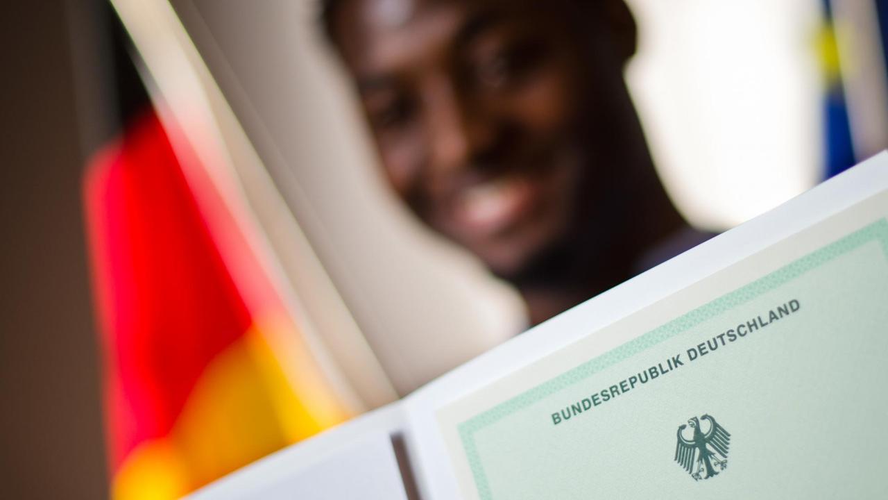 Ein Mann aus Kamerun bei einer Einbürgerungszeremonie mit einer Einbürgerungsurkunde der Bundesrepublik Deutschland. Ein Mann aus Kamerun bei einer Einbürgerungszeremonie mit einer Einbürgerungsurkunde der Bundesrepublik Deutschland.