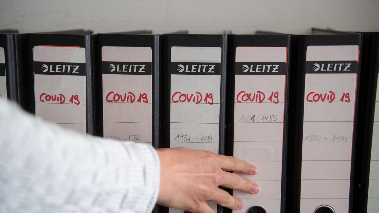 Ordner in eine Regalreihe sind mit COVID-19 beschriftet. Ordner in eine Regalreihe sind mit COVID-19 beschriftet.