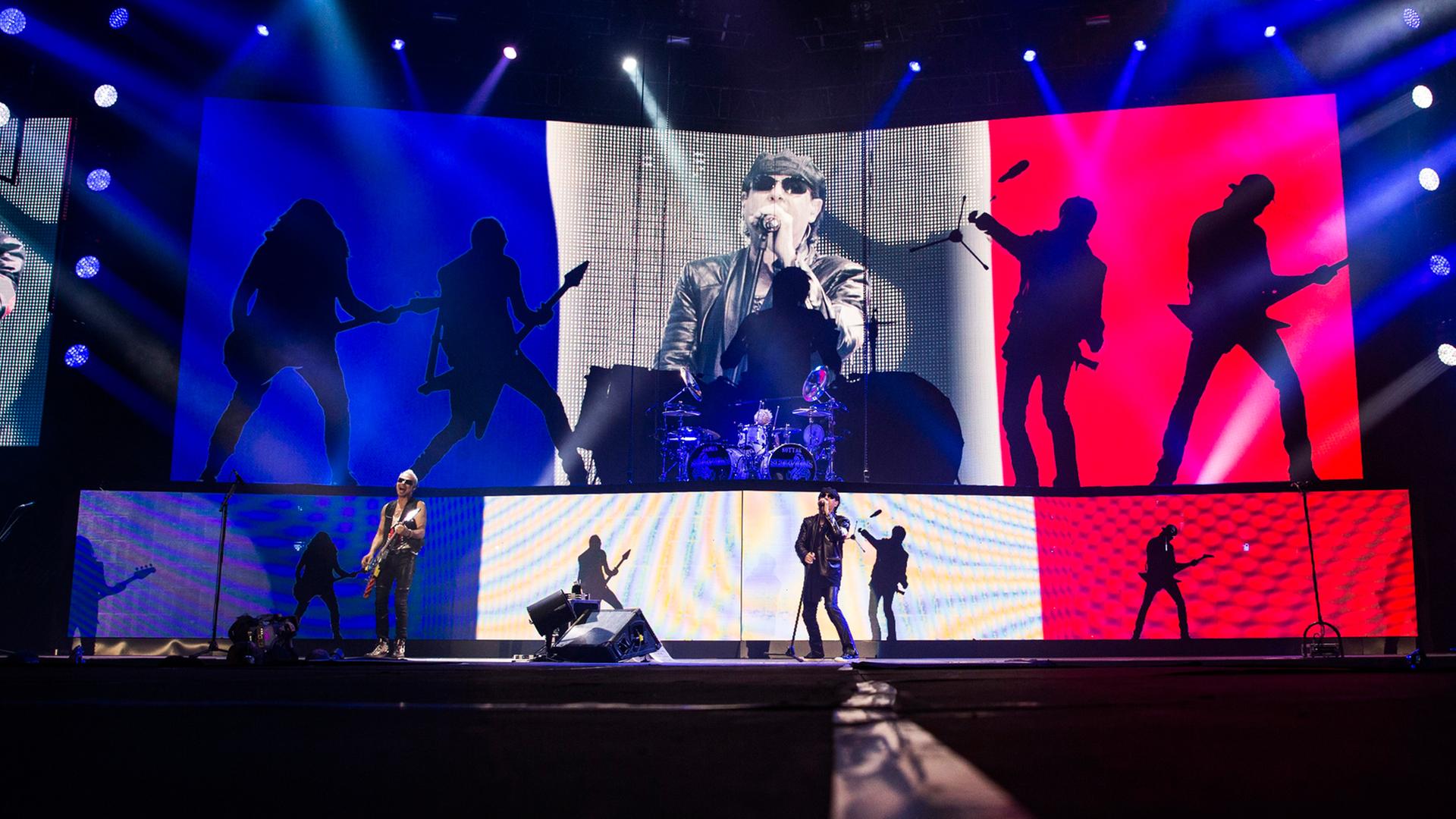 Die Scorpions spielen vor einer Projektion der französichen Nationalfarben bei ihrem Konzert in Paris.