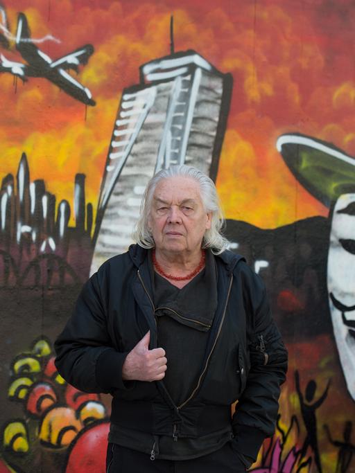Theaterchef Willy Praml steht vor einem Graffiti der Blockupy-Bewegung.