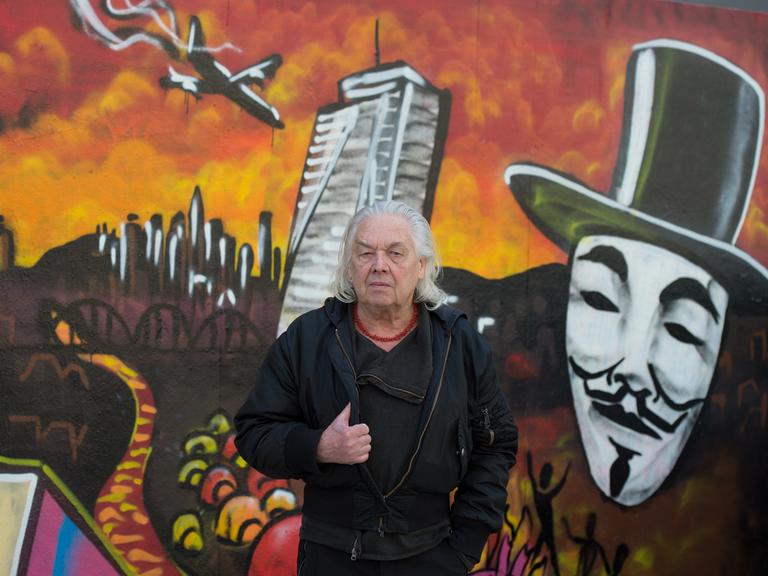 Theaterchef Willy Praml steht vor einem Graffiti der Blockupy-Bewegung.