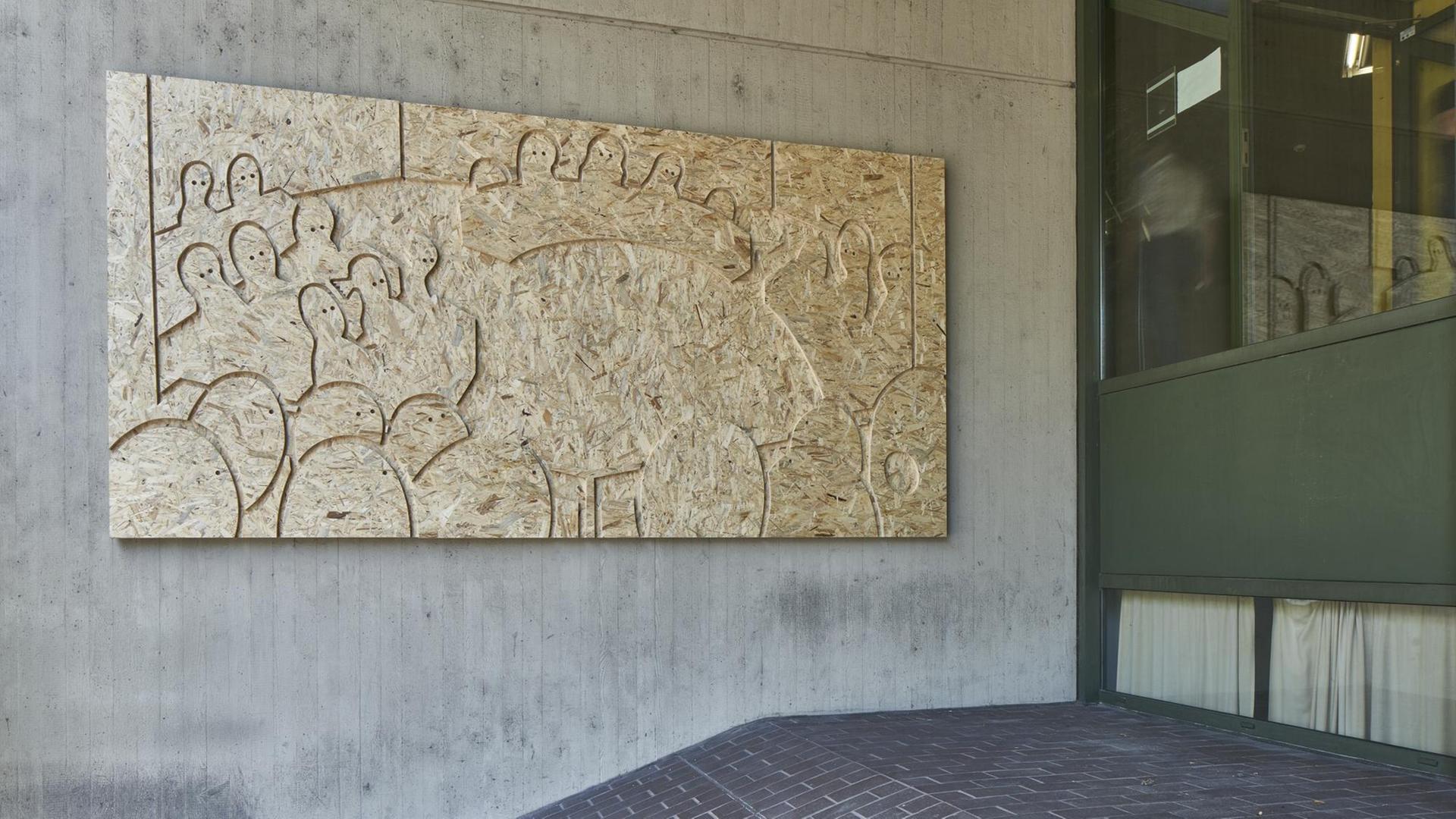 Ein Holzrelief zeigt Besucher und ihren Blick in den Gerichtssaal.