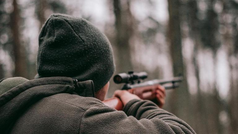 Ein Mann geht im Wald mit einem Gewehr jagen. Ein Mann geht im Wald mit einem Gewehr jagen.