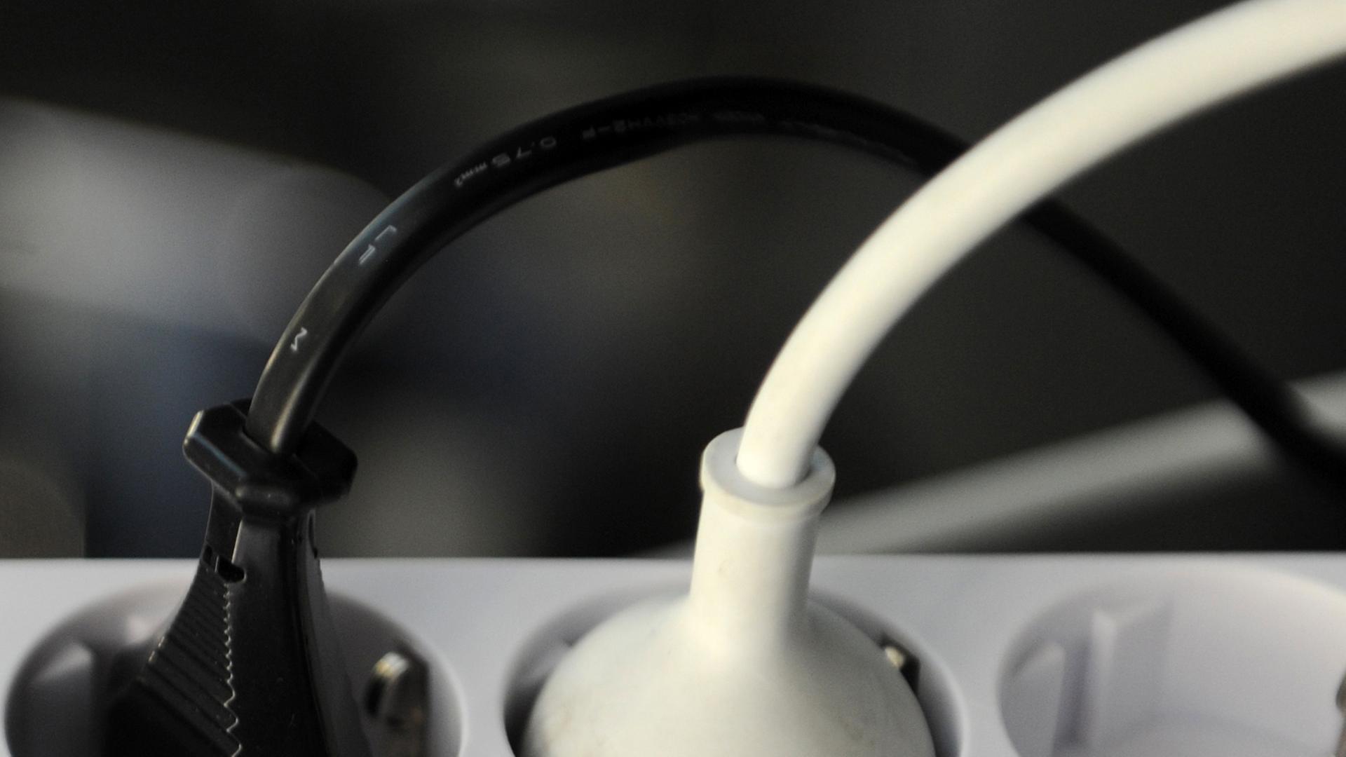 Zwei Stromkabel mit Stecker sind in an einer Mehrfachsteckdose angeschlossen. Zwei Stromkabel mit Stecker sind in an einer Mehrfachsteckdose angeschlossen.