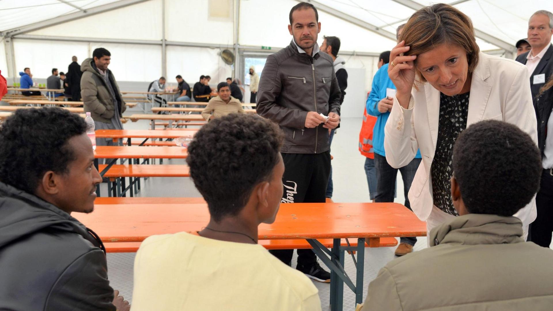 Die rheinland-pfälzische Ministerpräsidentin Malu Dreyer (r, SPD) spricht am 17.08.2015 in einem Aufenthaltszelt auf dem Flughafen Frankfurt-Hahn in Lautzenhausen (Rhein-Hunsrück-Kreis) mit Bewohnern. Auf dem Hahn sind zur Zeit 198 Flüchtlinge der Außenstelle der Aufnahmeeinrichtung für Asylbewerber (AfA) in Ingelheim untergebracht.