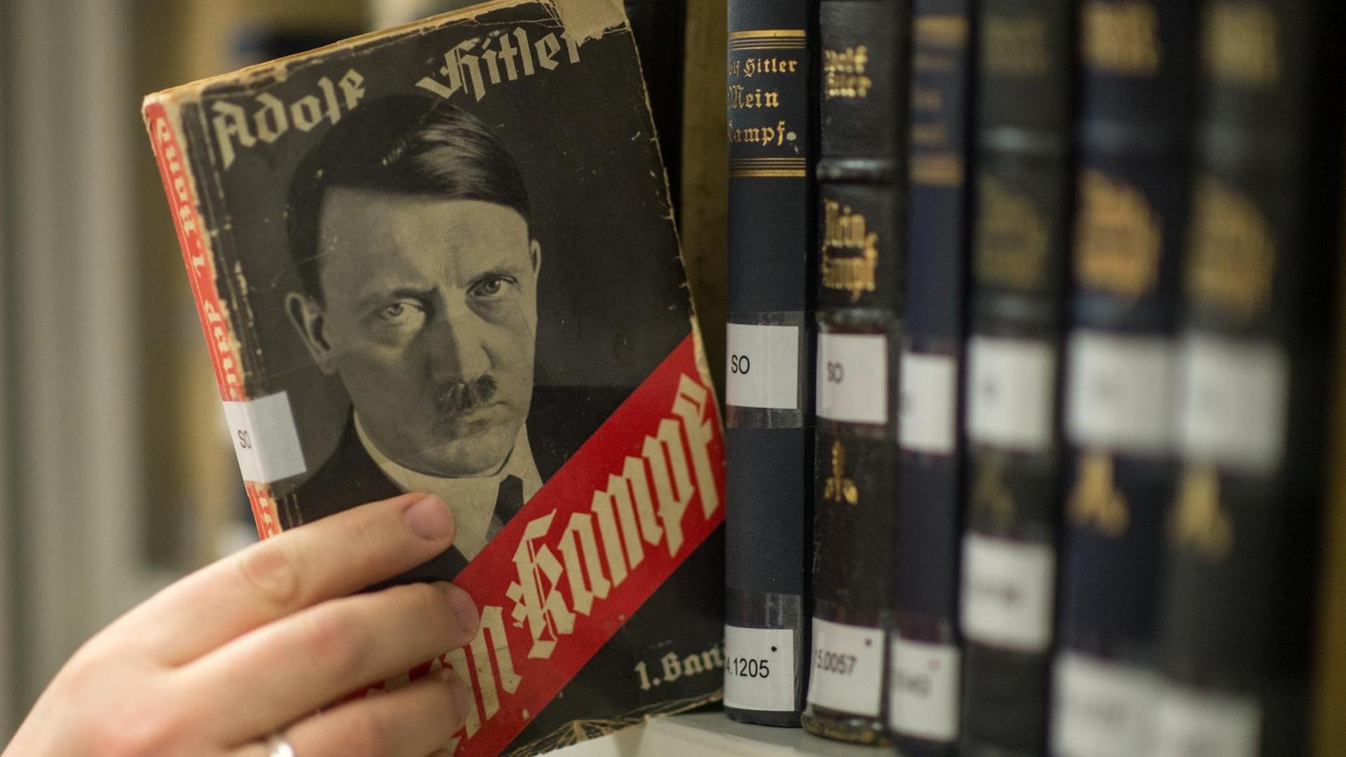 Man sieht, wie jemand eine Ausgabe von Hitlers "Mein Kampf" aus dem Jahr 1933 aus dem Regal zieht. Man sieht, wie jemand eine Ausgabe von Hitlers "Mein Kampf" aus dem Jahr 1933 aus dem Regal zieht.