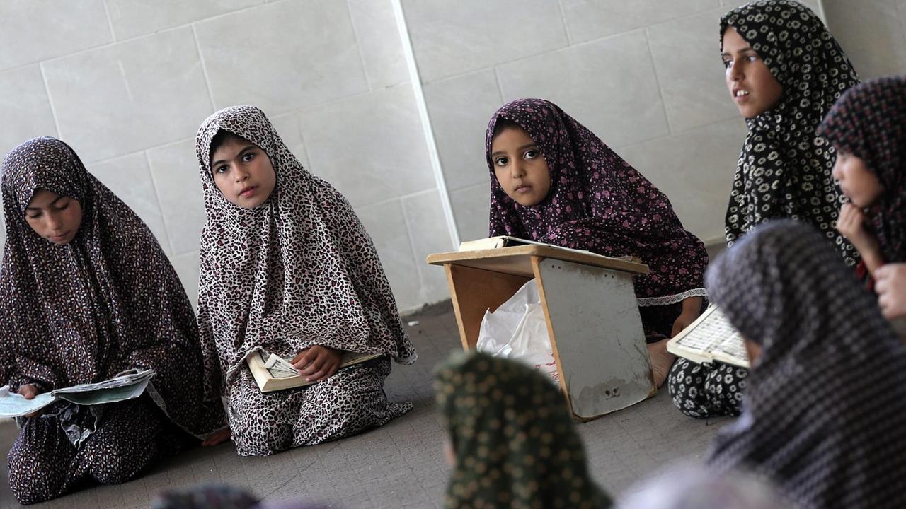 Sie sehen muslimische Schülerinnen mit Kopftuch, die im Koran lesen. Sie sehen muslimische Schülerinnen mit Kopftuch, die im Koran lesen.