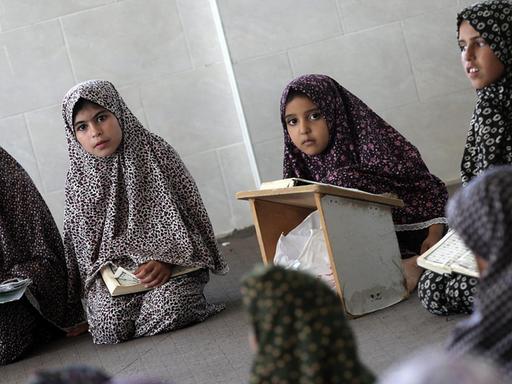 Sie sehen muslimische Schülerinnen mit Kopftuch, die im Koran lesen.