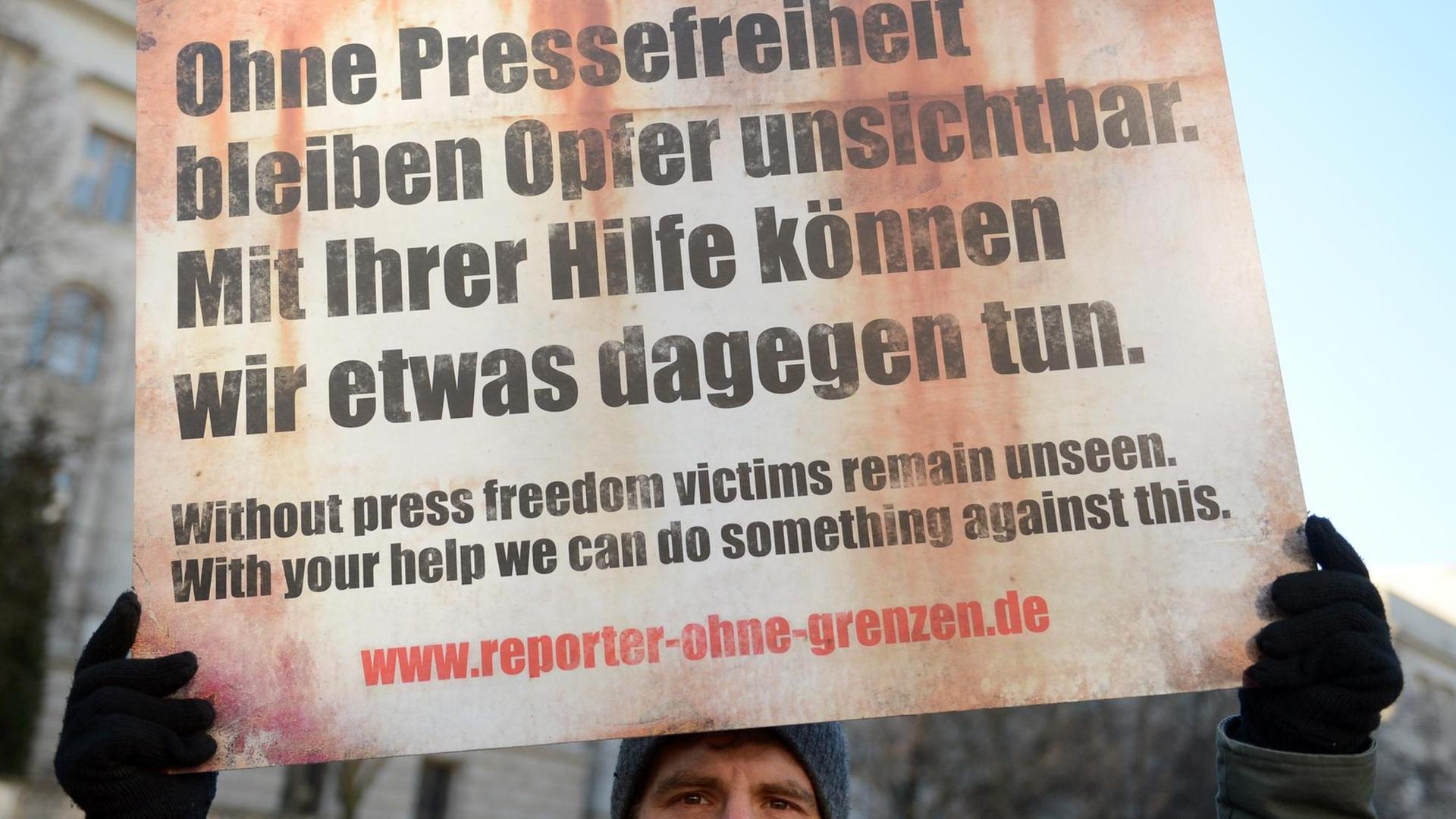Mann hält Protestschild für die Pressefreiheit in die Luft Mann hält Protestschild für die Pressefreiheit in die Luft