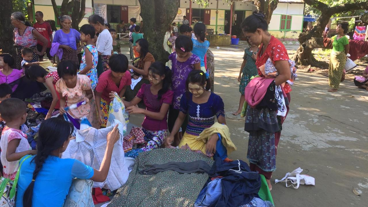 Geflüchtete buddhistische Familien - vor allem Frauen wühlen in Sittwe in Kleiderspenden, die auf dem Boden liegen. Geflüchtete buddhistische Familien - vor allem Frauen wühlen in Sittwe in Kleiderspenden, die auf dem Boden liegen.