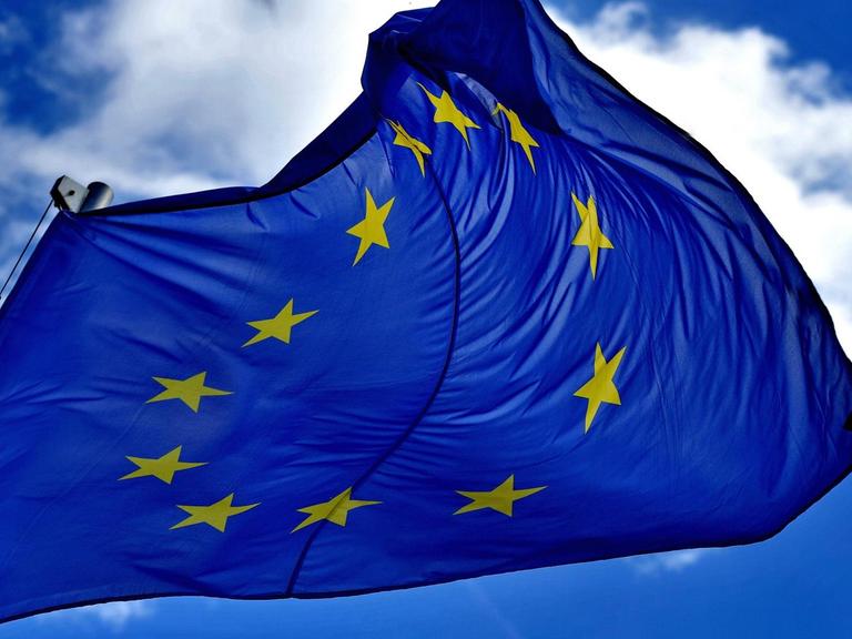 Eine EU-Fahne flattert vor fast wolkenlosem Himmel im Wind.