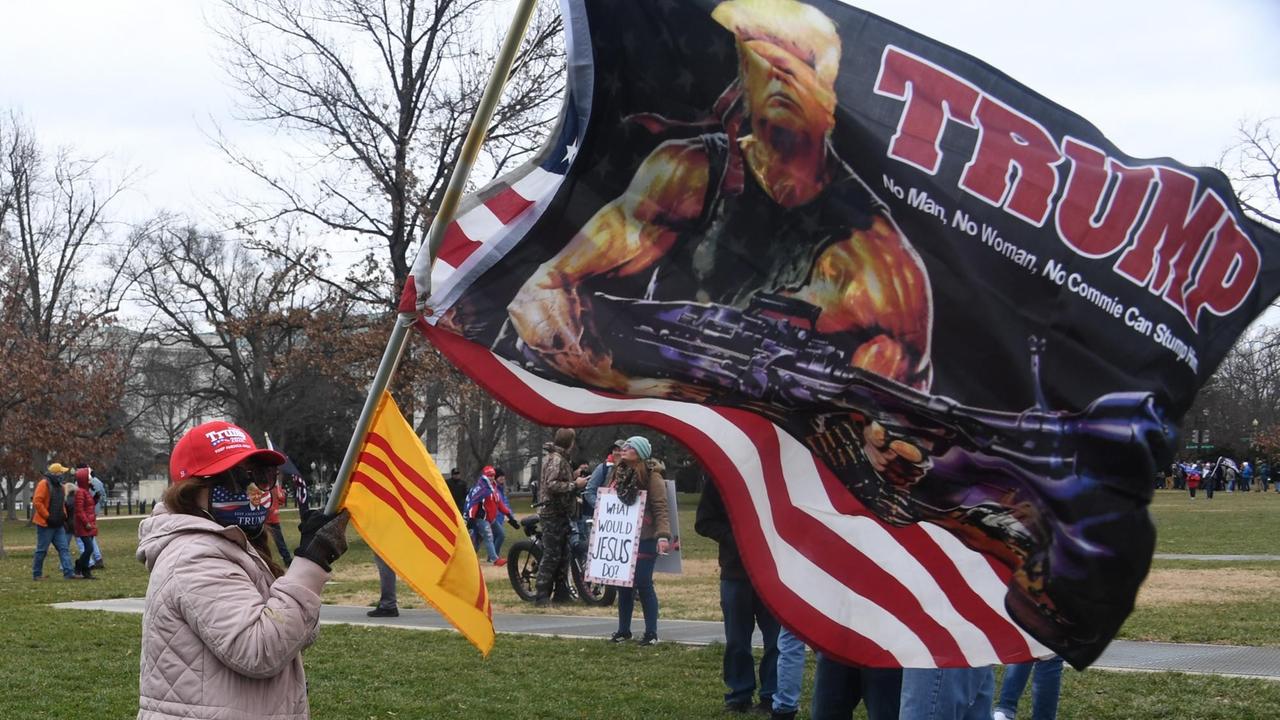 Trump-Unterstützer trägt Fahne mit Trump als Waffenträger Trump-Unterstützer trägt Fahne mit Trump als Waffenträger