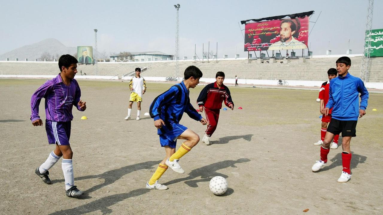 Afghanische Jungen im Stadion in Kabul am 24. Februar 2004. Im Hintergrund ist ein Poster des ehemaligen afghanischen Führers Ahmad Shah Massoud zu sehen, auf dem die Tugenden seines Märtyrertodes gepriesen werden. Afghanische Jungen im Stadion in Kabul am 24. Februar 2004. Im Hintergrund ist ein Poster des ehemaligen afghanischen Führers Ahmad Shah Massoud zu sehen, auf dem die Tugenden seines Märtyrertodes gepriesen werden.
