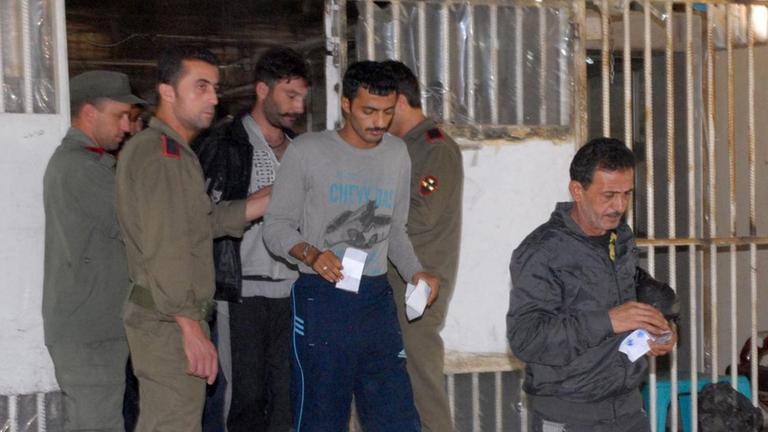 Am 11. Juni 2014 werden diese Häftlinge aus einem Gefängnis in Damasakus entlassen. Das Bild zeigt Menschen, die mit Papieren in der Hand einen vergitterten Bereich verlassen dürfen, Wärter sehen zu. Am 11. Juni 2014 werden diese Häftlinge aus einem Gefängnis in Damasakus entlassen. Das Bild zeigt Menschen, die mit Papieren in der Hand einen vergitterten Bereich verlassen dürfen, Wärter sehen zu.