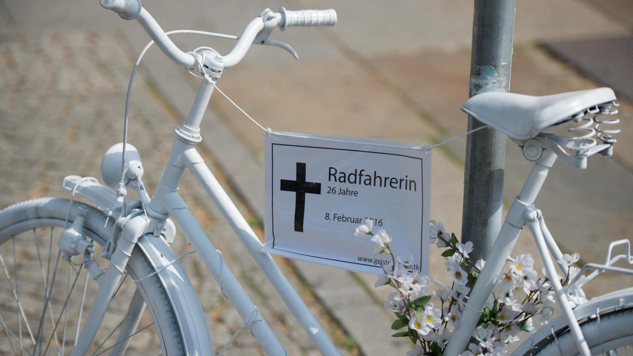 Ein weißes Fahrrad mit der Aufschrift "Radfahrerin, 26 Jahre" erinnert an einer Straßenkreuzung in Dresden an eine tödlich verunglückte Radlerin. 

