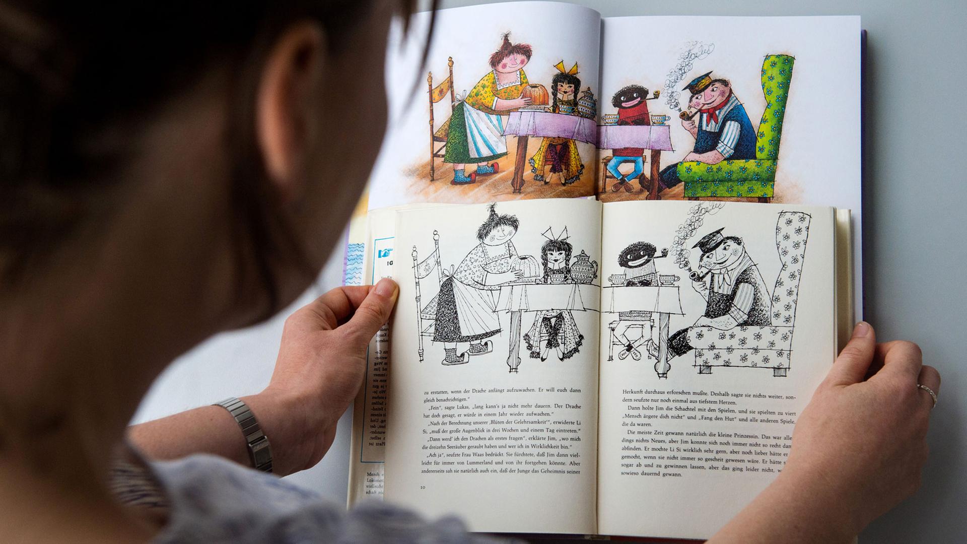 Eine Frau hält eine alte und eine neue Ausgabe des Kinderbuchs "Jim Knopf und die wilde 13" des Autors Michael Ende mit Illustrationen von Franz Josef Tripp in den Händen. Eine Frau hält eine alte und eine neue Ausgabe des Kinderbuchs "Jim Knopf und die wilde 13" des Autors Michael Ende mit Illustrationen von Franz Josef Tripp in den Händen.