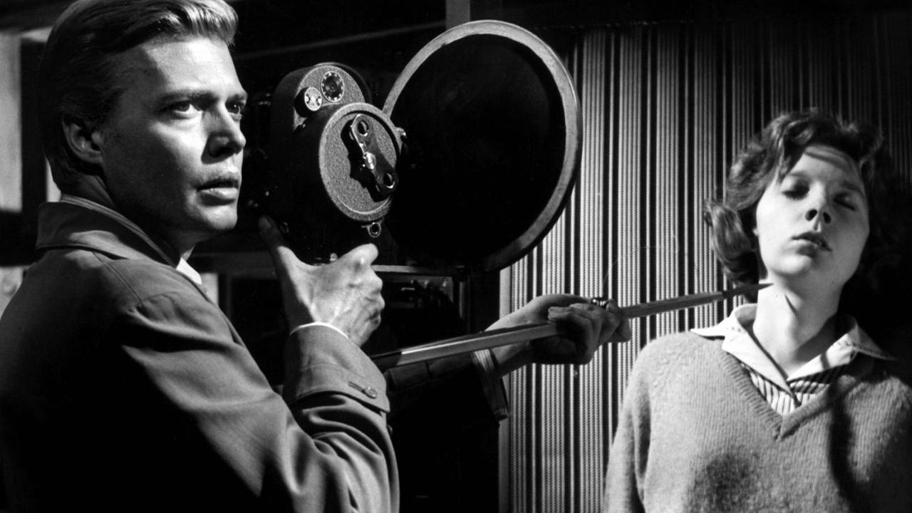 Karlheinz Böhm schultert eine Kamera und bedroht eine Frau mit einem spitzen Gegenstand. Karlheinz Böhm schultert eine Kamera und bedroht eine Frau mit einem spitzen Gegenstand.