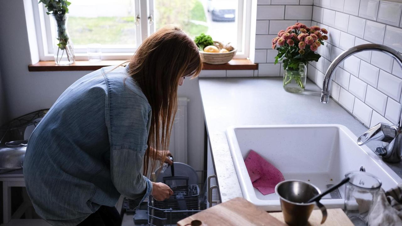 Eine Frau räumt die Spülmaschine ein.