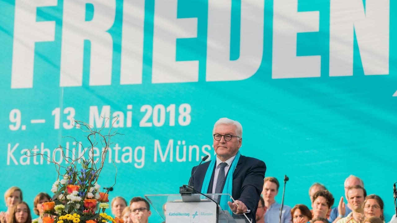 Bundespräsident Steinmeier steht hinter einem Rednerpult. Im Hintergrund ist ein blaues Banner mit dem Motto des diesjährigen Katholikentages "Suche Frieden" in weißer Schrift zu sehen.   
