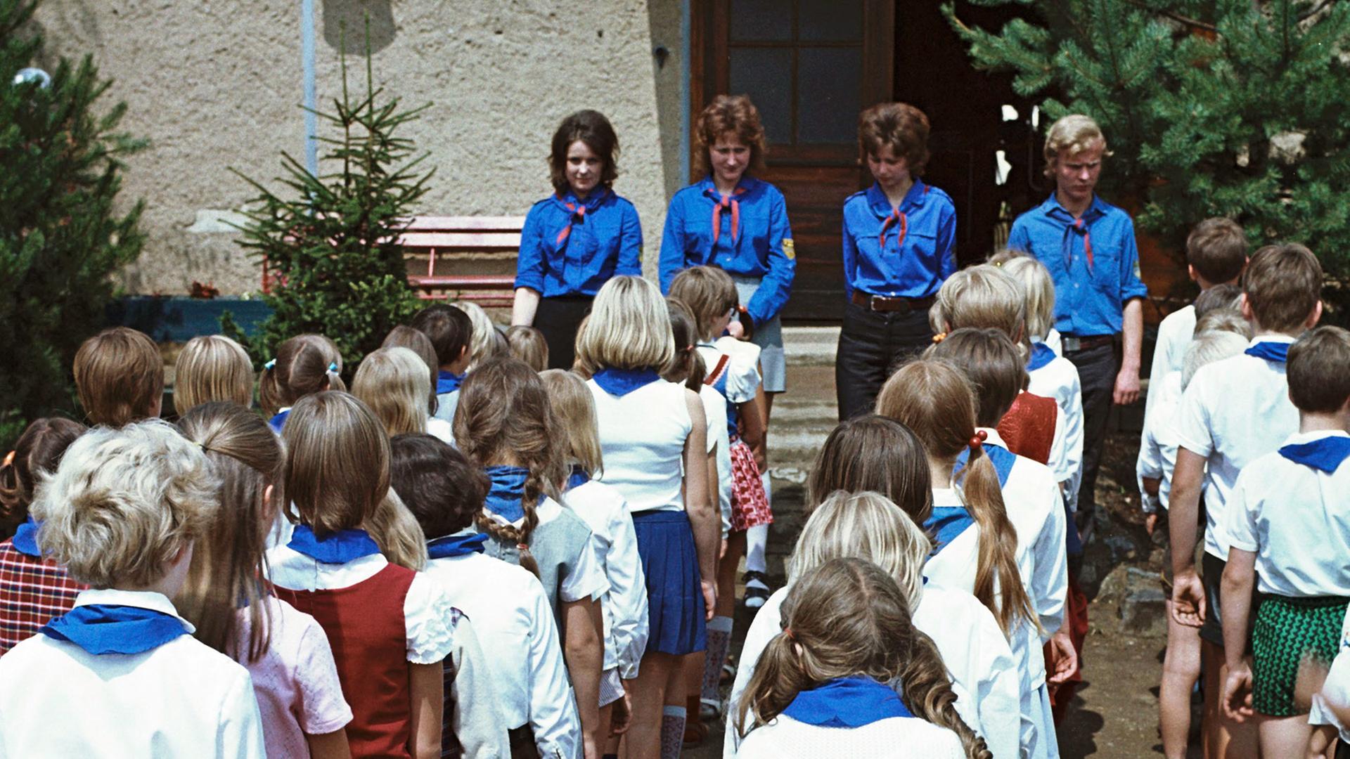 Kinder in Pionierkleidung mit blauen Halstüchern und ihre Betreuer von der FDJ bei einem Appell im Ferienheim des VEB Zemag Zeitz in Schneeberg, in dem die Schüler im Sommer 1972 einen Teil ihrer Schulferien verbringen Kinder in Pionierkleidung mit blauen Halstüchern und ihre Betreuer von der FDJ bei einem Appell im Ferienheim des VEB Zemag Zeitz in Schneeberg, in dem die Schüler im Sommer 1972 einen Teil ihrer Schulferien verbringen