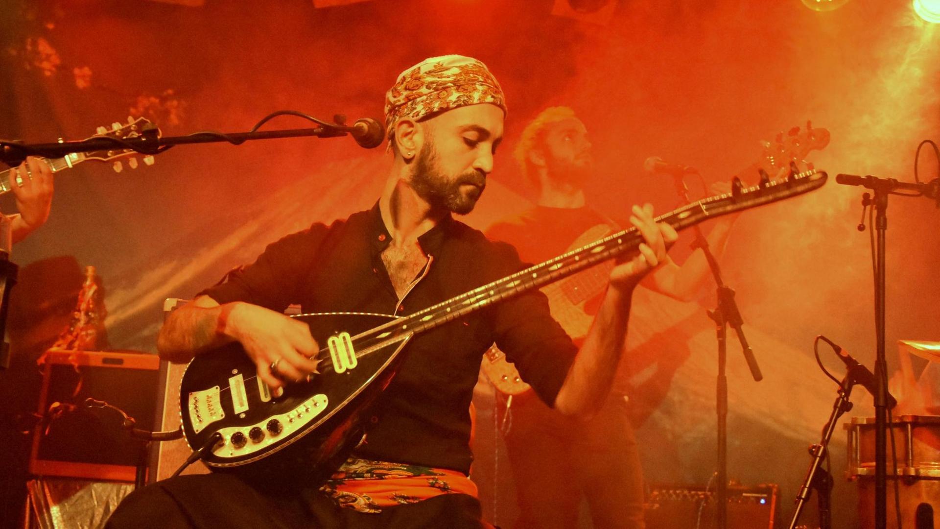 Der Berliner Musiker Adir Jan auf spielt auf der Bühne eine elektrisch verstärkte Langhalslaute Der Berliner Musiker Adir Jan auf spielt auf der Bühne eine elektrisch verstärkte Langhalslaute