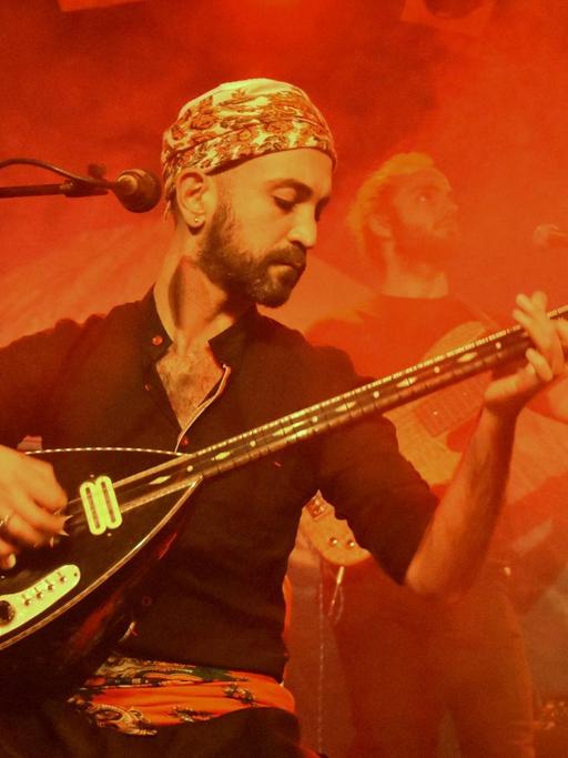Der Berliner Musiker Adir Jan auf spielt auf der Bühne eine elektrisch verstärkte Langhalslaute