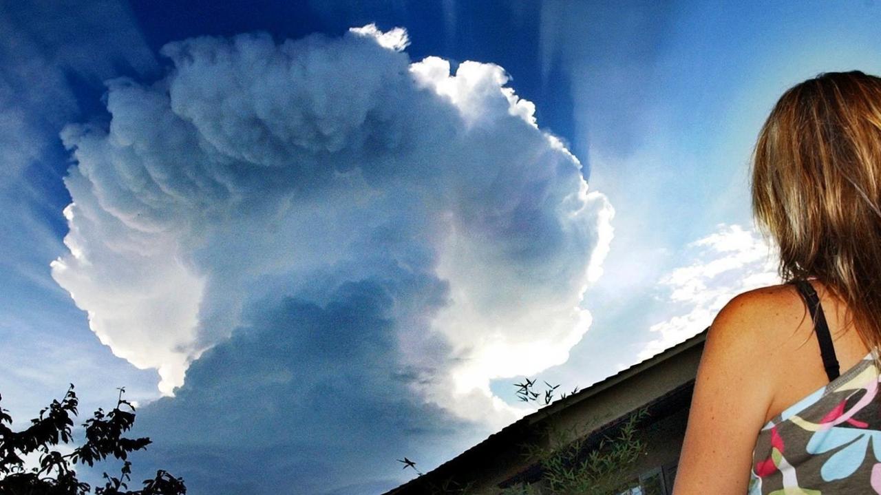 Eine Frau schaut sich eine ungewöhnliche Wolkenformation am Himmel an. Eine Frau schaut sich eine ungewöhnliche Wolkenformation am Himmel an.