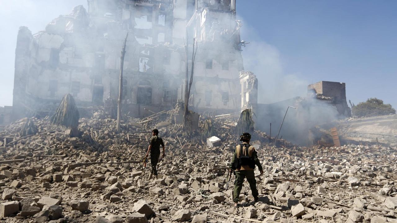 Huthi-Kämpfer vor den Ruinen eines Hauses in Sanaa, das angeblich durch Luftangriffe der saudischen Koalition zerstört wurde.
