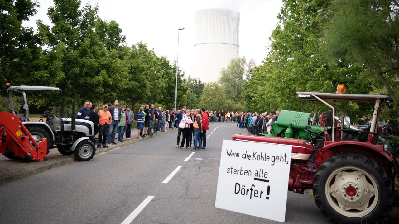 Umweltministerin Schulze wird vor dem Braunkohle-Kraftwerk "Schwarze Pumpe" von Demonstranten mit einem Plakat "Wenn die Kohle geht, sterben alle Dörfer" empfangen.
