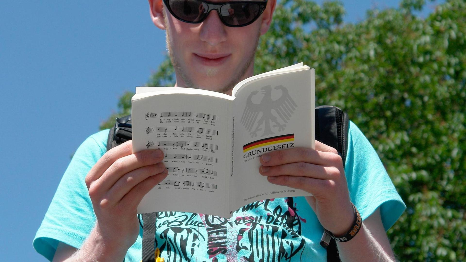 Ein junger Mann schaut beim Laufen in die Gesetzessammlung des Grundgesetzes. Ein junger Mann schaut beim Laufen in die Gesetzessammlung des Grundgesetzes.