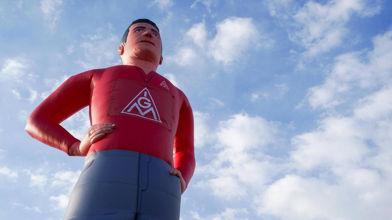 Eine große aufgeblasene Puppe mit IGM-Logo auf der Brust vor blauem Himmel Eine große aufgeblasene Puppe mit IGM-Logo auf der Brust vor blauem Himmel