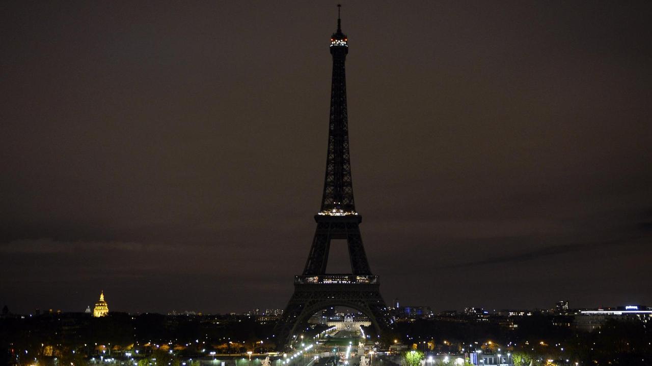 Man sieht den Eiffelturm aus einiger Entfernung in der Nacht. Straßenlaternen leuchten. Man sieht den Eiffelturm aus einiger Entfernung in der Nacht. Straßenlaternen leuchten.