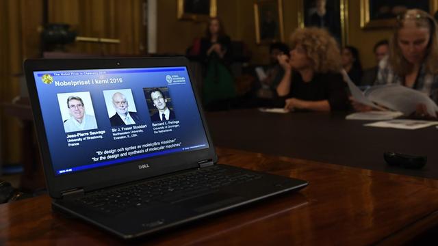 Die künftigen Nobelpreisträger Sauvage, Stoddart und Feringa (von links nach rechts) auf einem Bildschirm bei der Pressekonferenz in Stockholm.