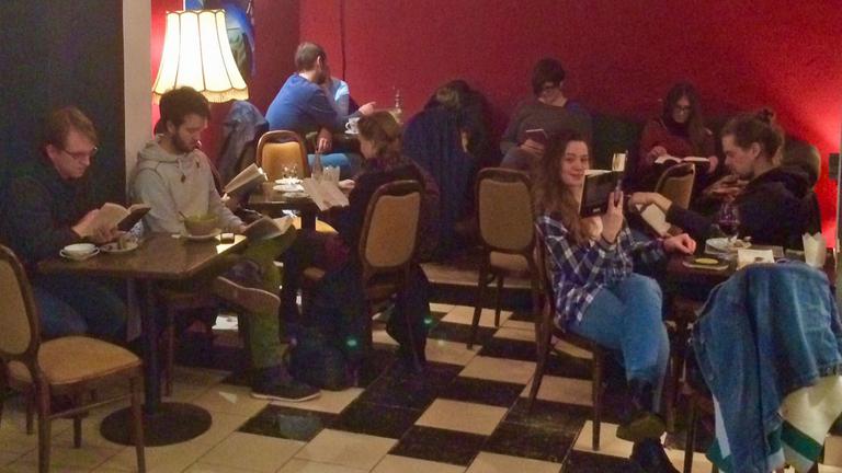 Junge Menschen sitzen im Kieler Café Godot im Dämmerlicht und lesen.