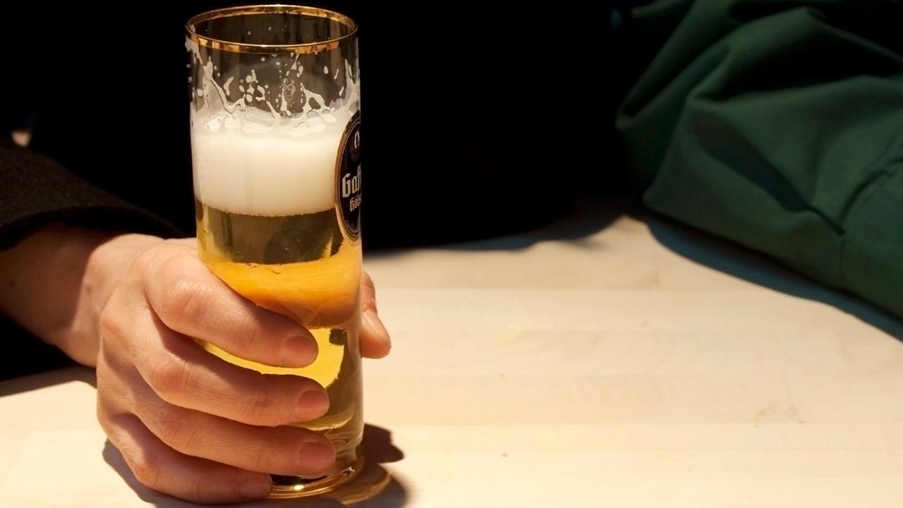 Thekengast hält sich an einem Glas Kölsch fest Thekengast hält sich an einem Glas Kölsch fest