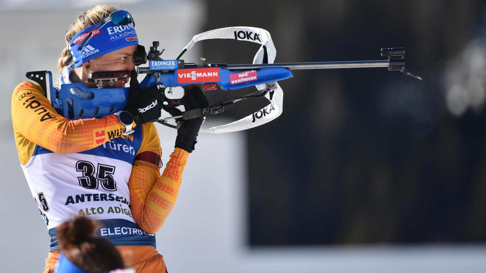 Die Sportlerin legt am Schiess-Stand das Gewehr an und zielt Die Sportlerin legt am Schiess-Stand das Gewehr an und zielt