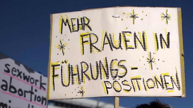 Eine Demonstrantin hält ein Schild mit der Aufschrift "Mehr Frauen in Führungspositionen" bei einer Kundgebung in Berlin.