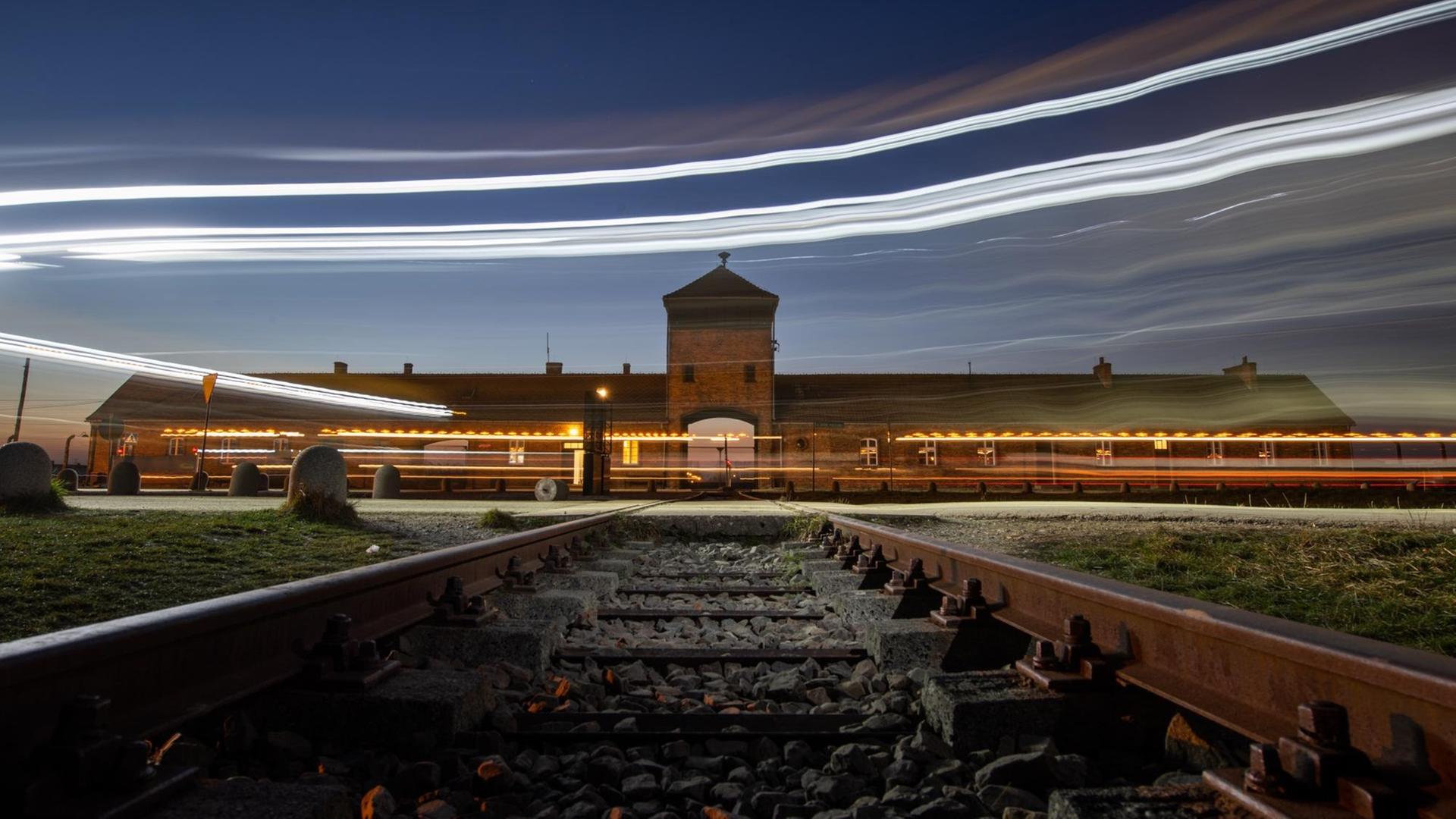 Lichter von vorbeifahrenden Autos sind vor dem Eingangsportal des ehemaligen Konzentrationslagers Auschwitz-Birkenau zu sehen. Lichter von vorbeifahrenden Autos sind vor dem Eingangsportal des ehemaligen Konzentrationslagers Auschwitz-Birkenau zu sehen.