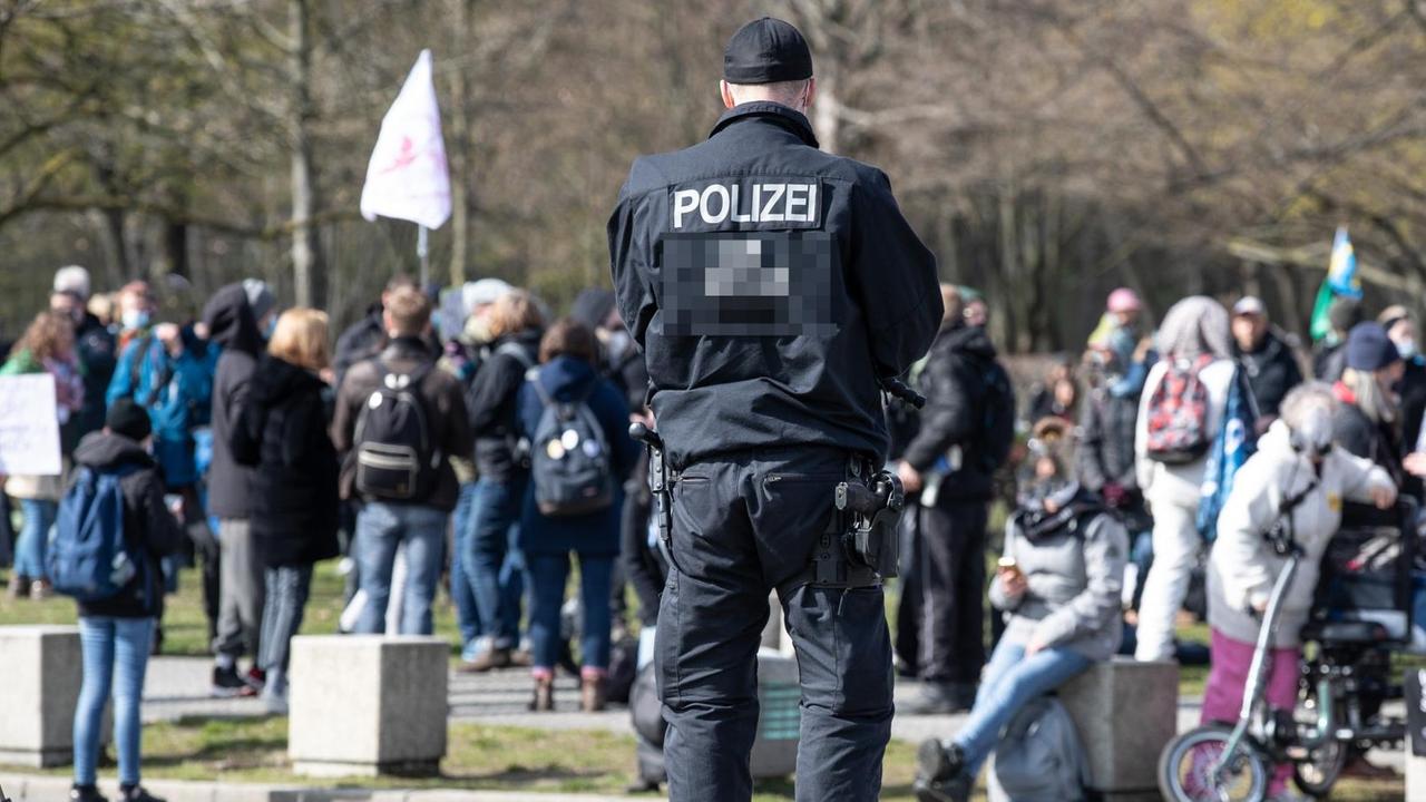 Ein Polizist bewacht eine Gruppe Demonstranten der Querdenker. Ein Polizist bewacht eine Gruppe Demonstranten der Querdenker.