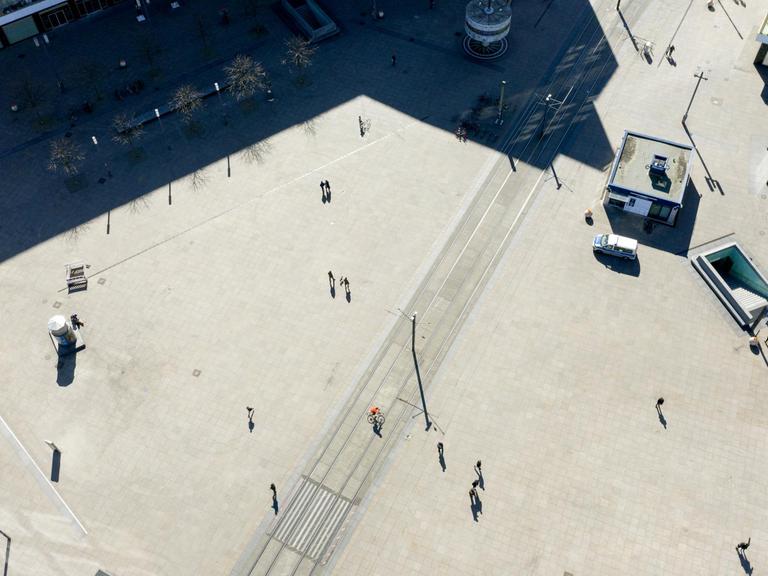 Vogelperspektive auf den Alexanderplatz, auf dem mit großem Abstand einige Menschen laufen.