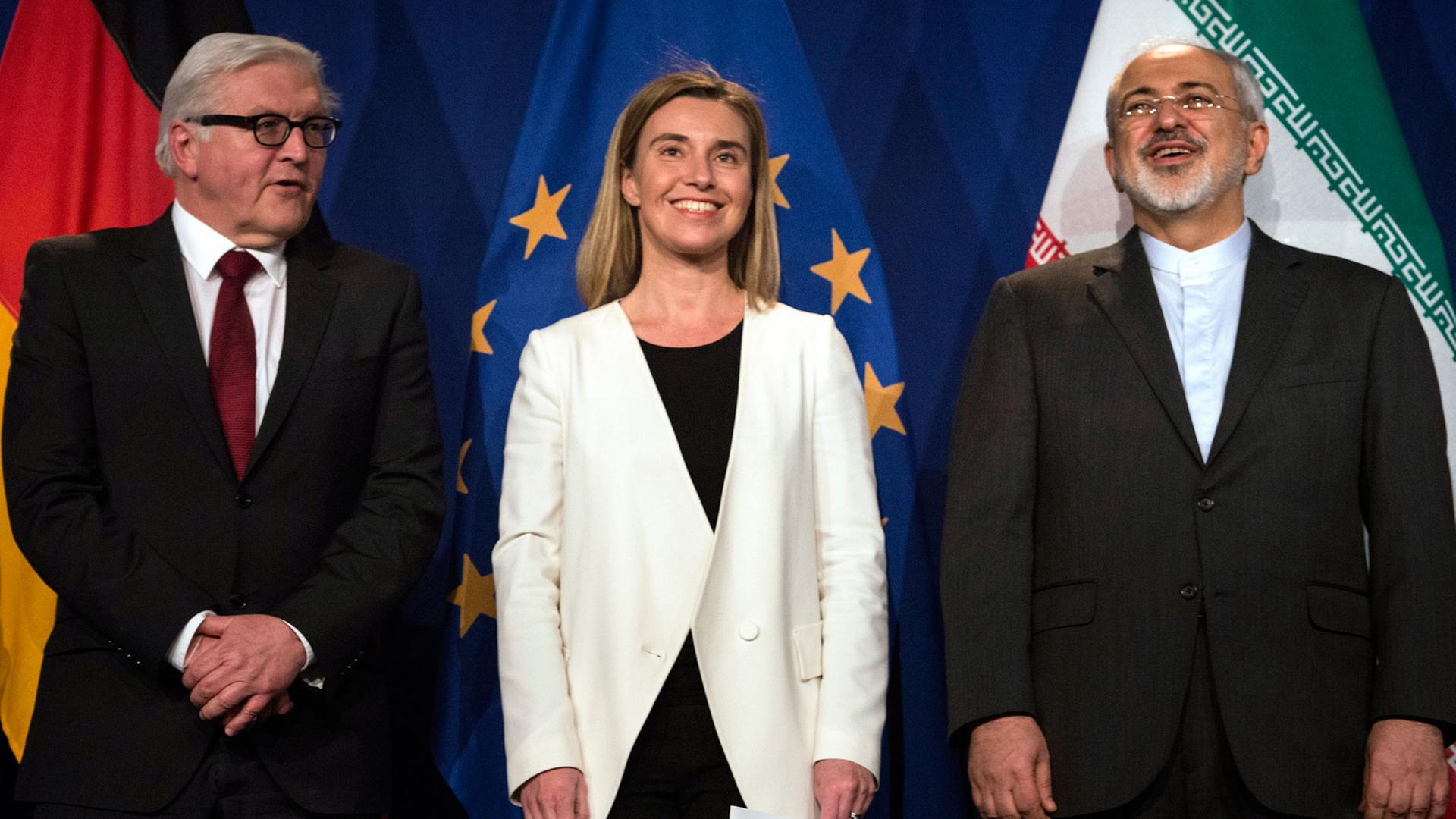 Bundesaußenminister Frank-Walter Steinmeier, die EU-Außenbeauftragte Federica Mogherini und der iranische Außenminister Javad Sarif stehen am 2. April 2015 vor Nationalflaggen in Lausanne. Bundesaußenminister Frank-Walter Steinmeier, die EU-Außenbeauftragte Federica Mogherini und der iranische Außenminister Javad Sarif stehen am 2. April 2015 vor Nationalflaggen in Lausanne.