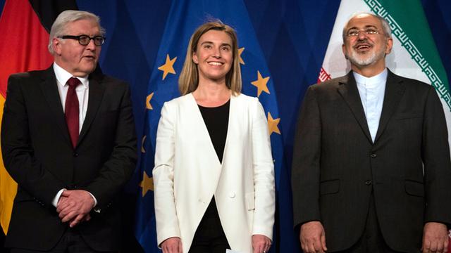 Bundesaußenminister Frank-Walter Steinmeier, die EU-Außenbeauftragte Federica Mogherini und der iranische Außenminister Javad Sarif stehen am 2. April 2015 vor Nationalflaggen in Lausanne.
