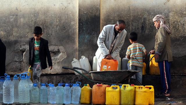 Männer und Kinder füllen an einer Wasserpumpe in Jemens Hauptstadt Sanaa Trinkwasser in Plastikkanister