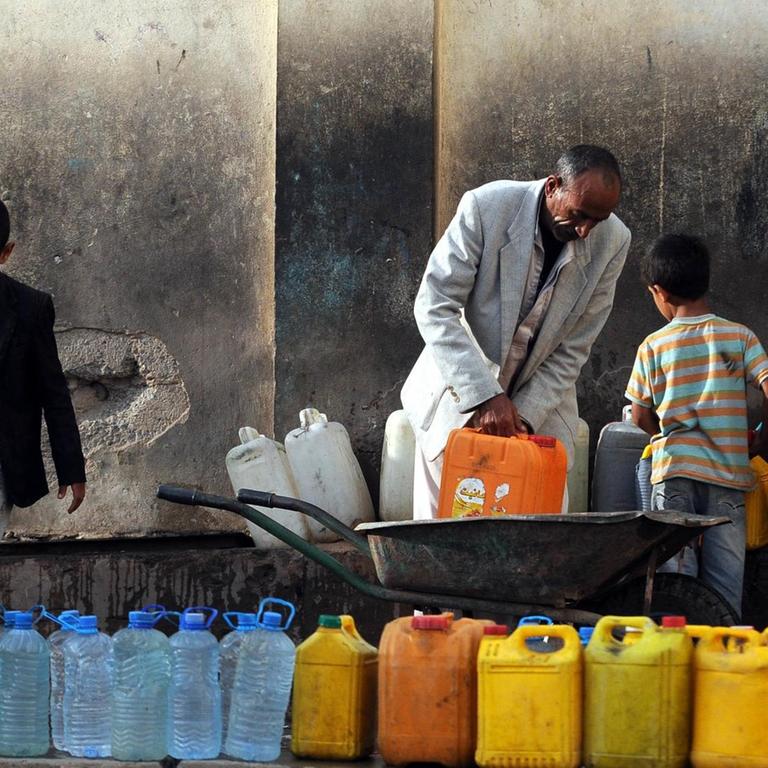 Männer und Kinder füllen an einer Wasserpumpe in Jemens Hauptstadt Sanaa Trinkwasser in Plastikkanister 