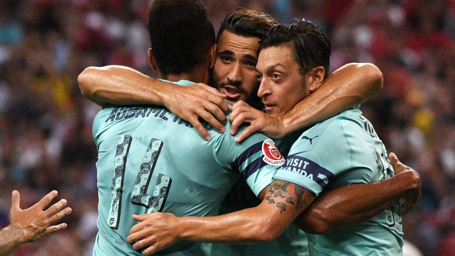 Mesut Özil (r) vom FC Arsenal bejubelt sein Tor zum 1:0 mit Pierre-Emerick Aubameyang (l) und Sead Kolasinac (28.7.208).