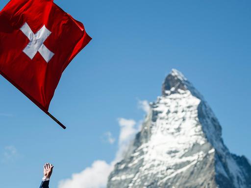 Eine hochgeworfene Schweizer Flagge vor der Spitze des Matterhorns