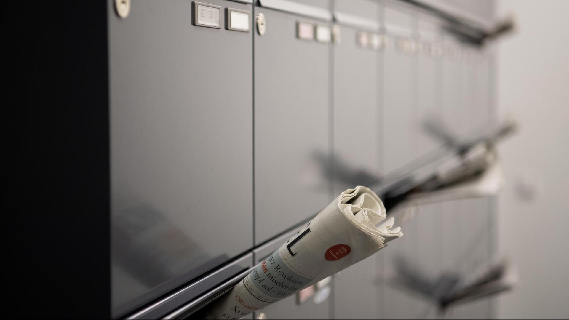 Mehrere Zeitungen stecken in Briefkästen im Flur eines Mehrfamilienhauses Mehrere Zeitungen stecken in Briefkästen im Flur eines Mehrfamilienhauses