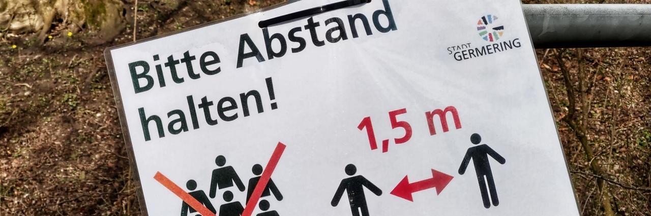 Auf einem an einem Laternenpfahl angebrachten Zettel steht: "Bitte Abstand halten". DIe Deutschen sind angewiesen in der Öffentlichkeit einen Mindestabstand von 1,5 Metern zueinander zu halten. Auf einem an einem Laternenpfahl angebrachten Zettel steht: "Bitte Abstand halten". DIe Deutschen sind angewiesen in der Öffentlichkeit einen Mindestabstand von 1,5 Metern zueinander zu halten.